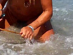 Зрелая женщина с пирсингом растянутых сосков и множеством пирсинга киски на пляже