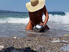 Femeie matură cu piercing-uri întinse pe sfârcuri și piercinguri multiple în pizdă pe plajă