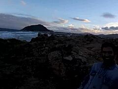 Deniz kenarındaki kayaların üzerinde sakso çeken genç bir kızın tahrik edici videosu